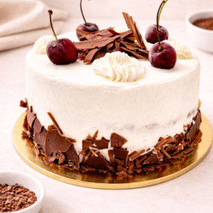 La clásica Tarta Selva Negra: bizcocho de chocolate húmedo con almíbar de Kirsch, relleno y cubierto con crema chantillí y cerezas. Un postre elegante y lleno de tradición.